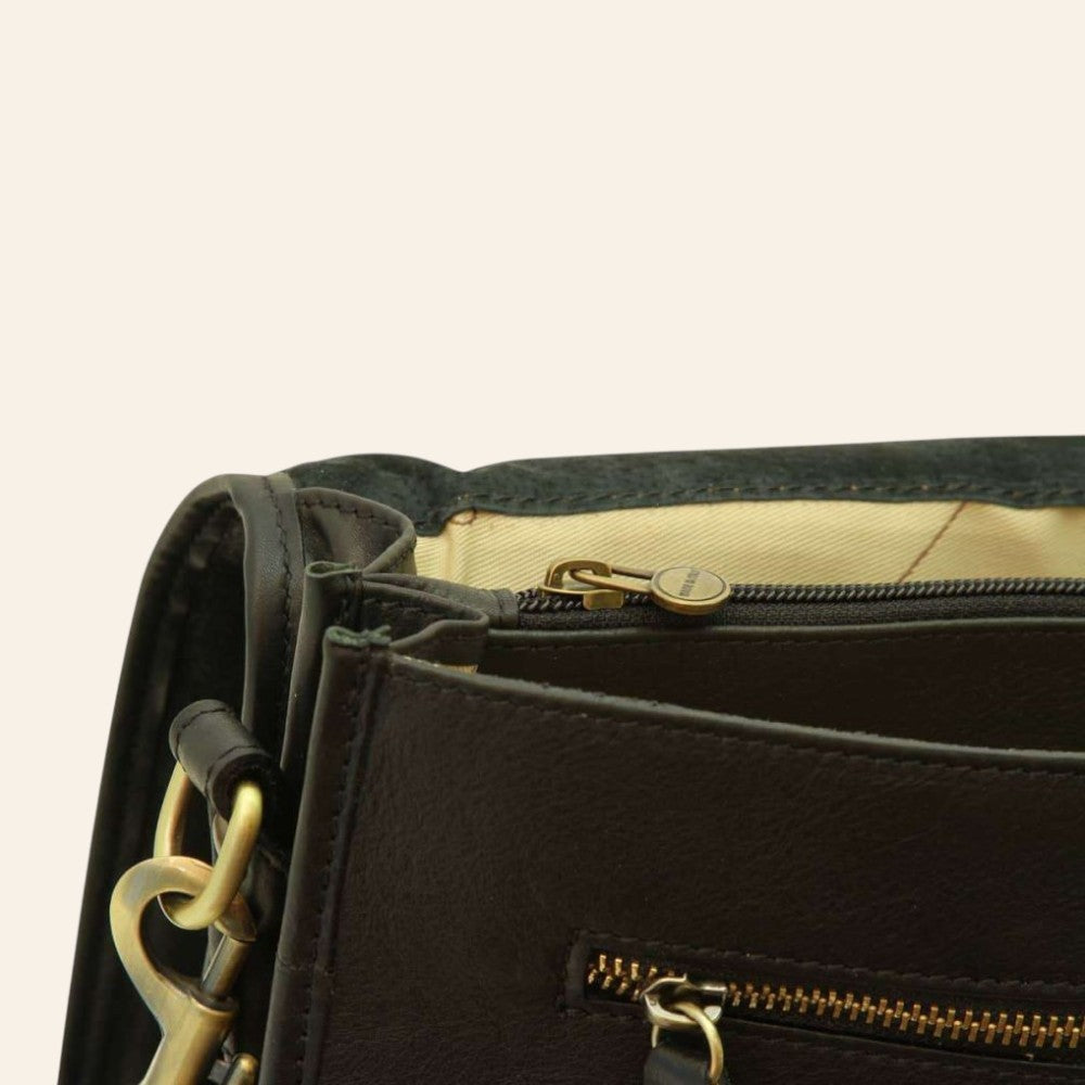 Dettaglio cartella in pelle scura: zip dorata, passanti e anello in metallo
