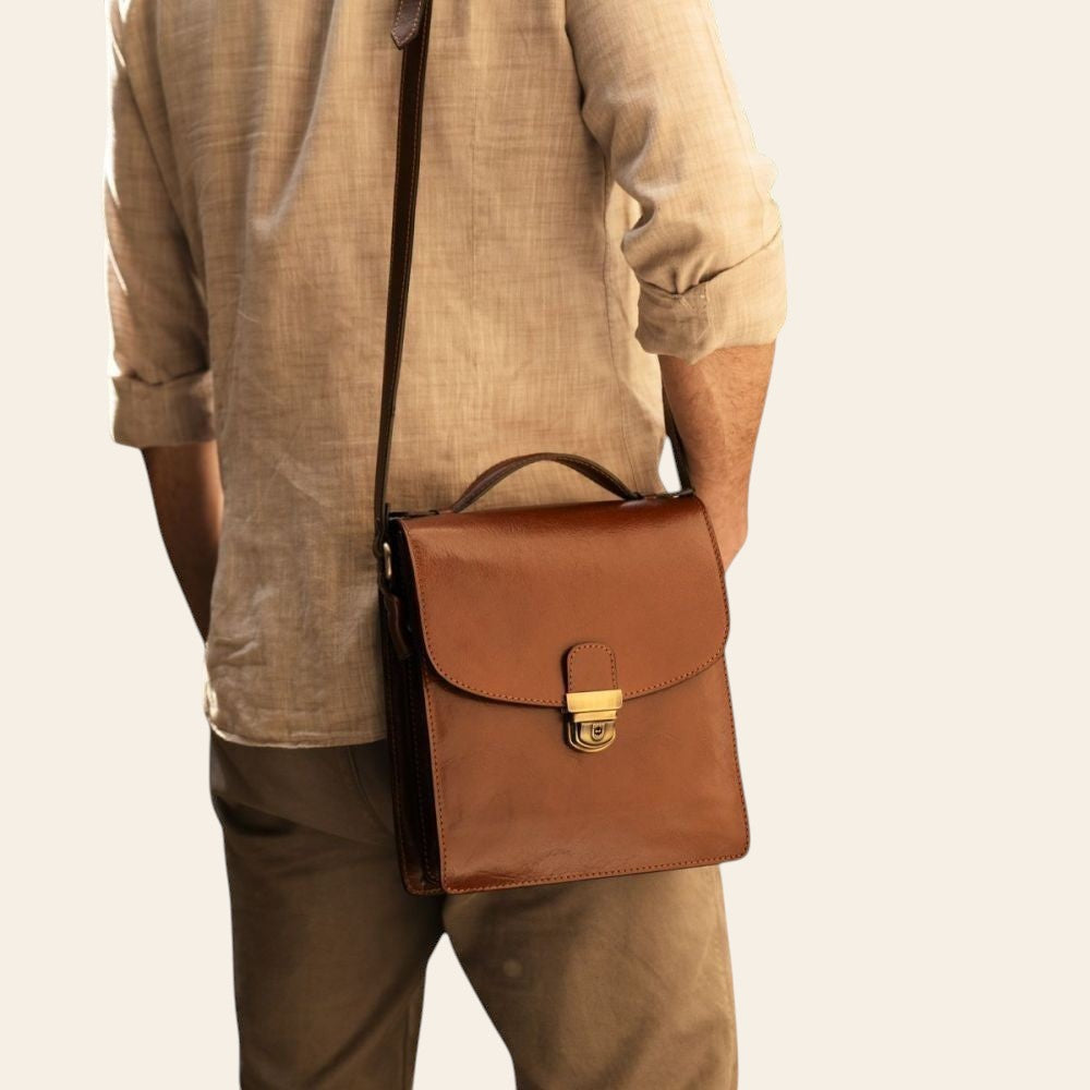 Borsa a tracolla in pelle marrone indossata con patta e chiusura a fibbia.