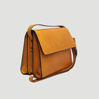 Borsa a tracolla ocra in vitello pieno fiore vista laterale con patta e laccetti.