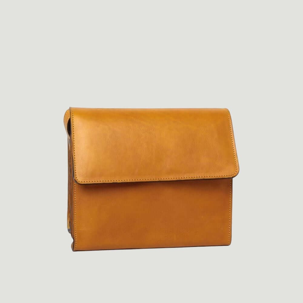 Borsa a tracolla ocra in vitello pieno fiore con patta frontale e cuciture.