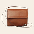 Borsa a tracolla in pelle color teak, patta con fibbia e tracolla regolabile.