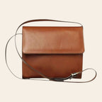Borsa a tracolla in pelle color teak, patta con fibbia e tracolla regolabile.