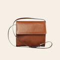 Borsa a tracolla in pelle color teak, patta con fibbia e tracolla regolabile.