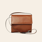 Borsa a tracolla in pelle color teak, patta con fibbia e tracolla regolabile.