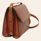Borsa a tracolla in pelle teak, vista laterale con fibbie e tracolla.