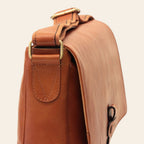 Borsa messenger in pelle cuoio vista laterale con fibbia e cuciture decorative.