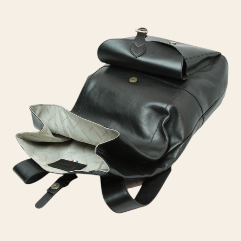 Zaino in pelle nero aperto: interno chiaro, tasche e tracolla con fibbia