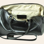 Interno del bauletto in pelle nera con fodera chiara, tasca e zip
