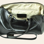 Interno del bauletto in pelle nera con fodera chiara, tasca e zip
