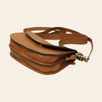 Borsa a tracolla marrone con fibbie metalliche e tracolla, vista dall’alto inclinata