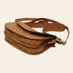 Borsa a tracolla marrone con fibbie metalliche e tracolla, vista dall’alto inclinata