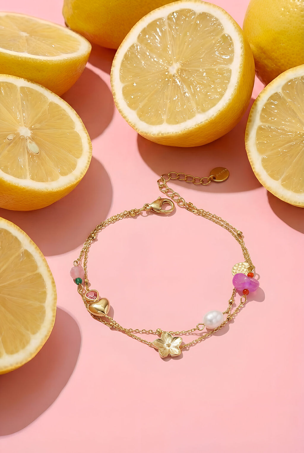 Braccialetto con ciondoli cuore fiore perla decorato con limoni freschi sullo sfondo.