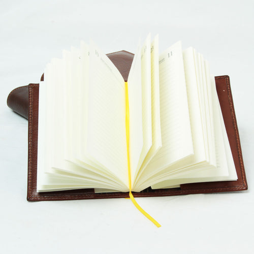 Agenda grande in pelle marrone, aperta con pagine su nastro giallo.
