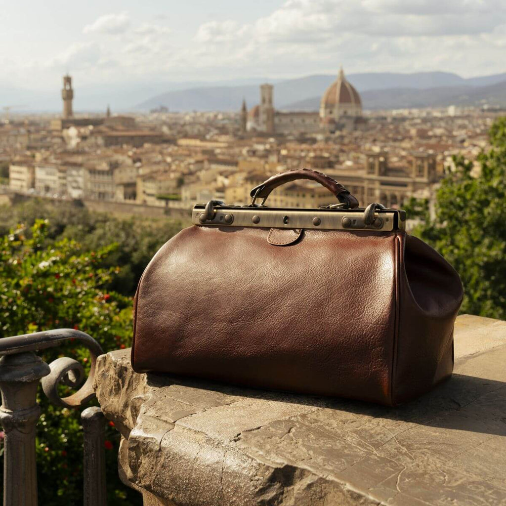 Borsa in pelle marrone con cerniera e manico rigido, dettagli borchie color ottone