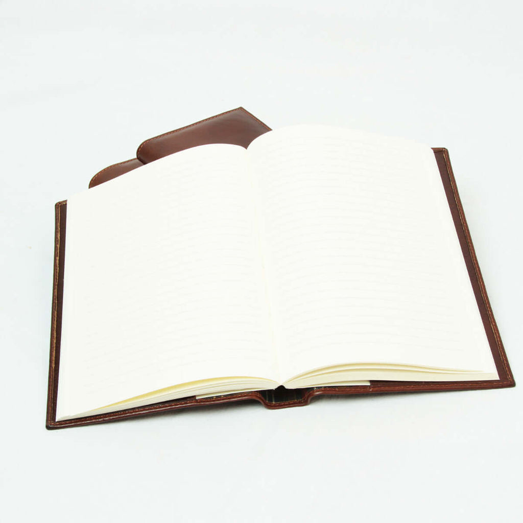 Diario in pelle marrone aperto con fogli bianchi e righe.