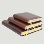 Diario in pelle marrone chiuso, impilato con etichette SMALL, MEDIUM, LARGE