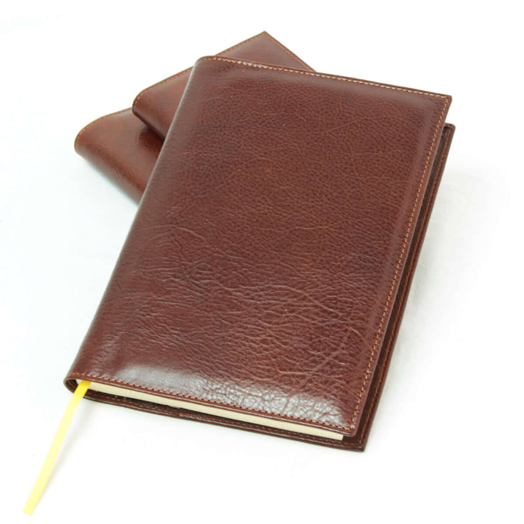 Diario grande in pelle marrone con segnalibro in stoffa gialla.
