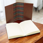 Diario in pelle marrone piccolo, aperto con pagine bianche e fodera a tartan.
