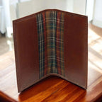 Diario in pelle marrone, vista frontale aperta con interno a motivo tartan.