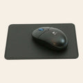 Tappetino per mouse in pelle nera con bordi cuciti e mouse ottico sopra