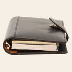 Organizer in pelle con chiusura a cinturino, fogli visibili e bottone metallico