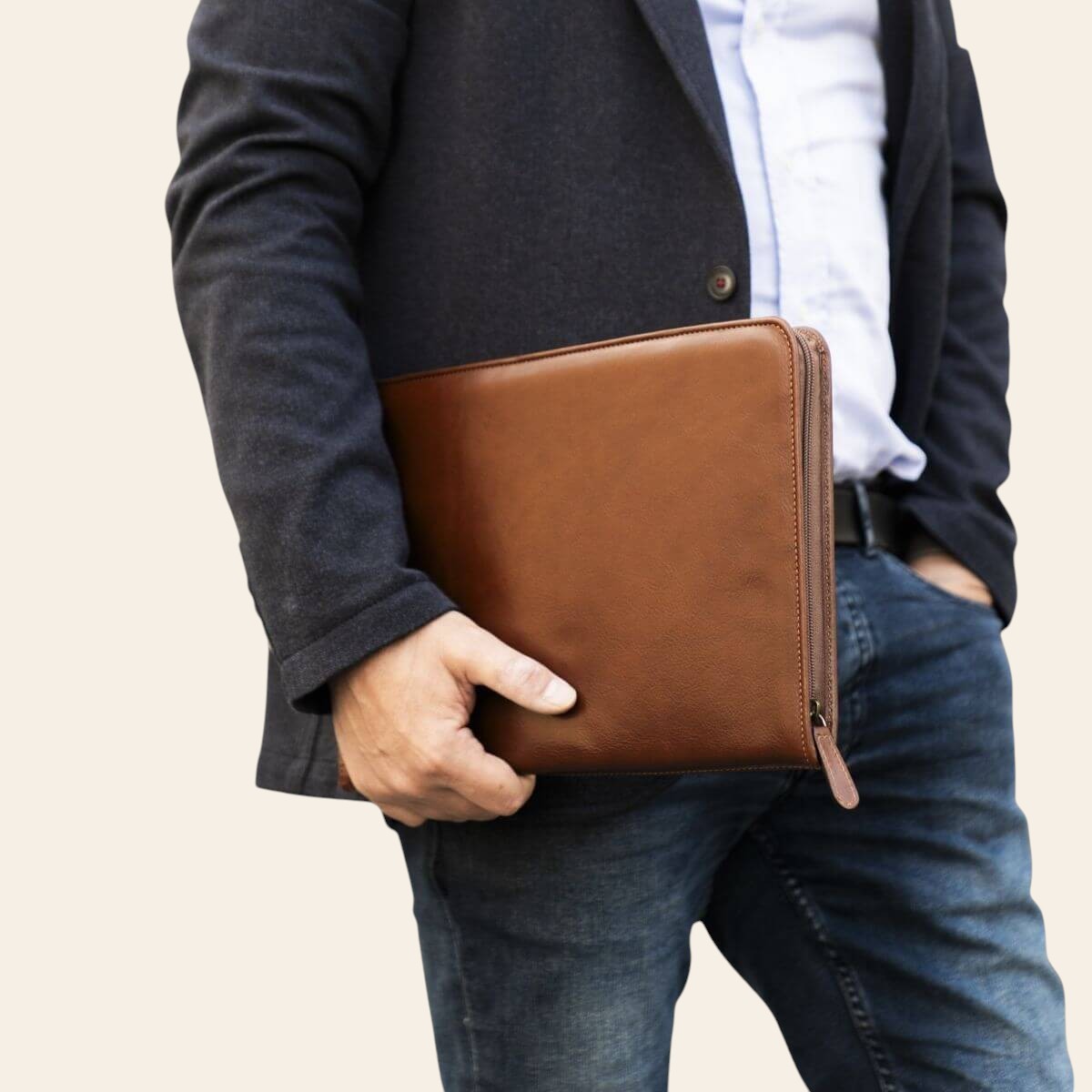 Porta documenti marrone effetto pelle in mano, chiusura con zip.
