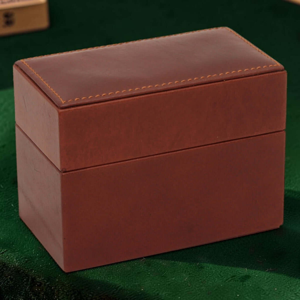 Scatola porta carte in pelle marrone chiusa con cuciture decorative sul coperchio.