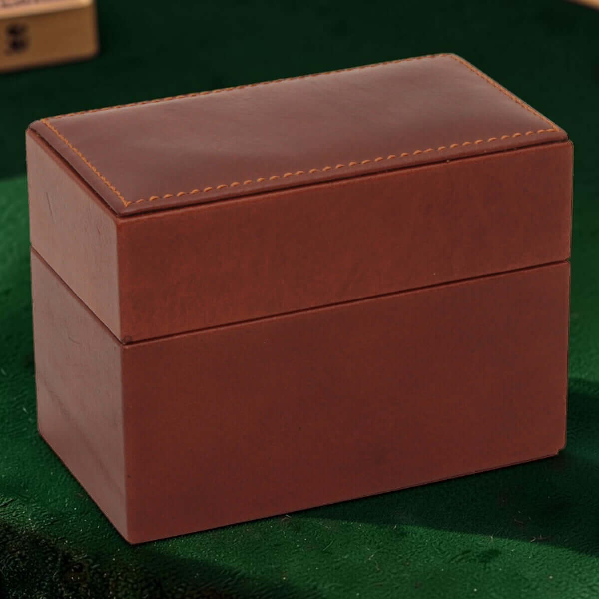 Scatola porta carte in pelle marrone chiusa con cuciture decorative sul coperchio.