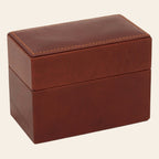 Scatola porta carte in pelle marrone chiusa con cuciture decorative sul coperchio.