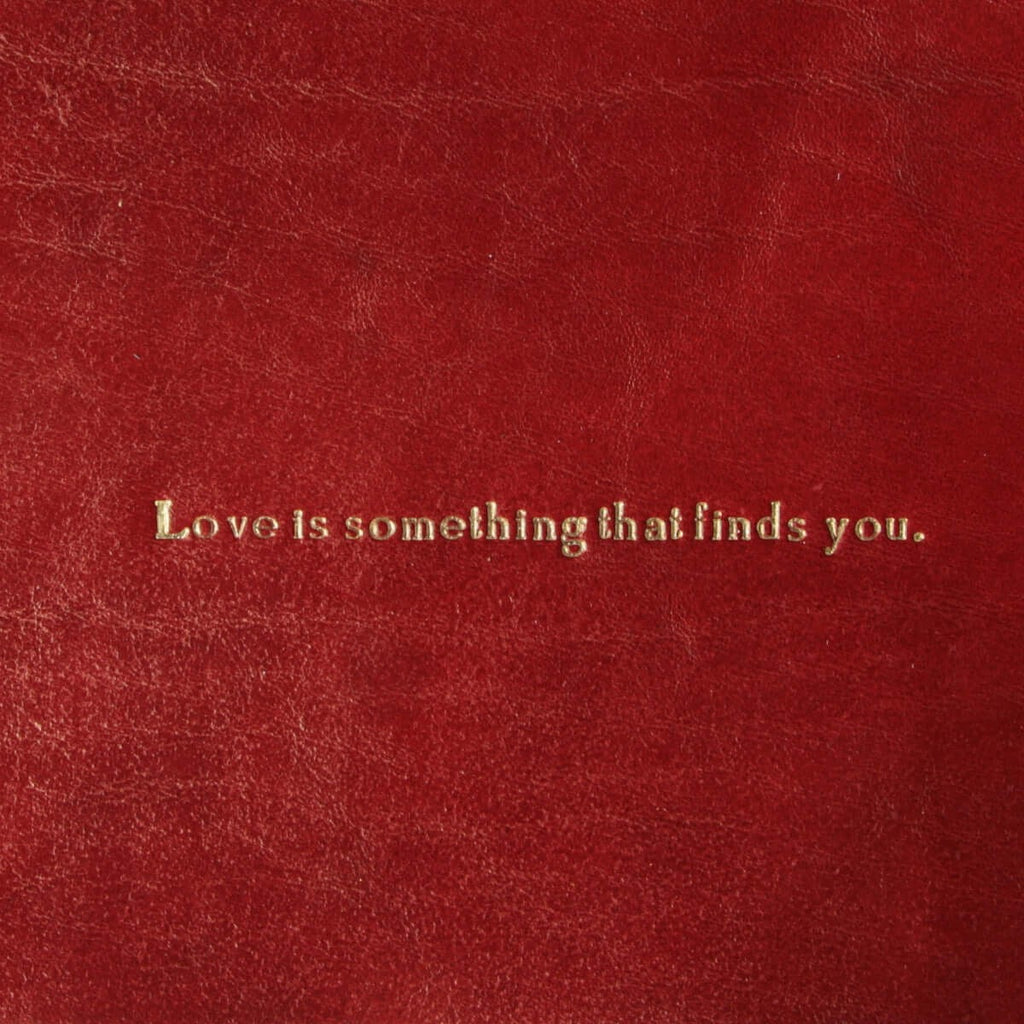 Piccolo vassoio in pelle rossa con frase “Love is something that finds you.” incisa