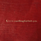 Vuotatasche in pelle rossa con scritta: Love is something that finds you.