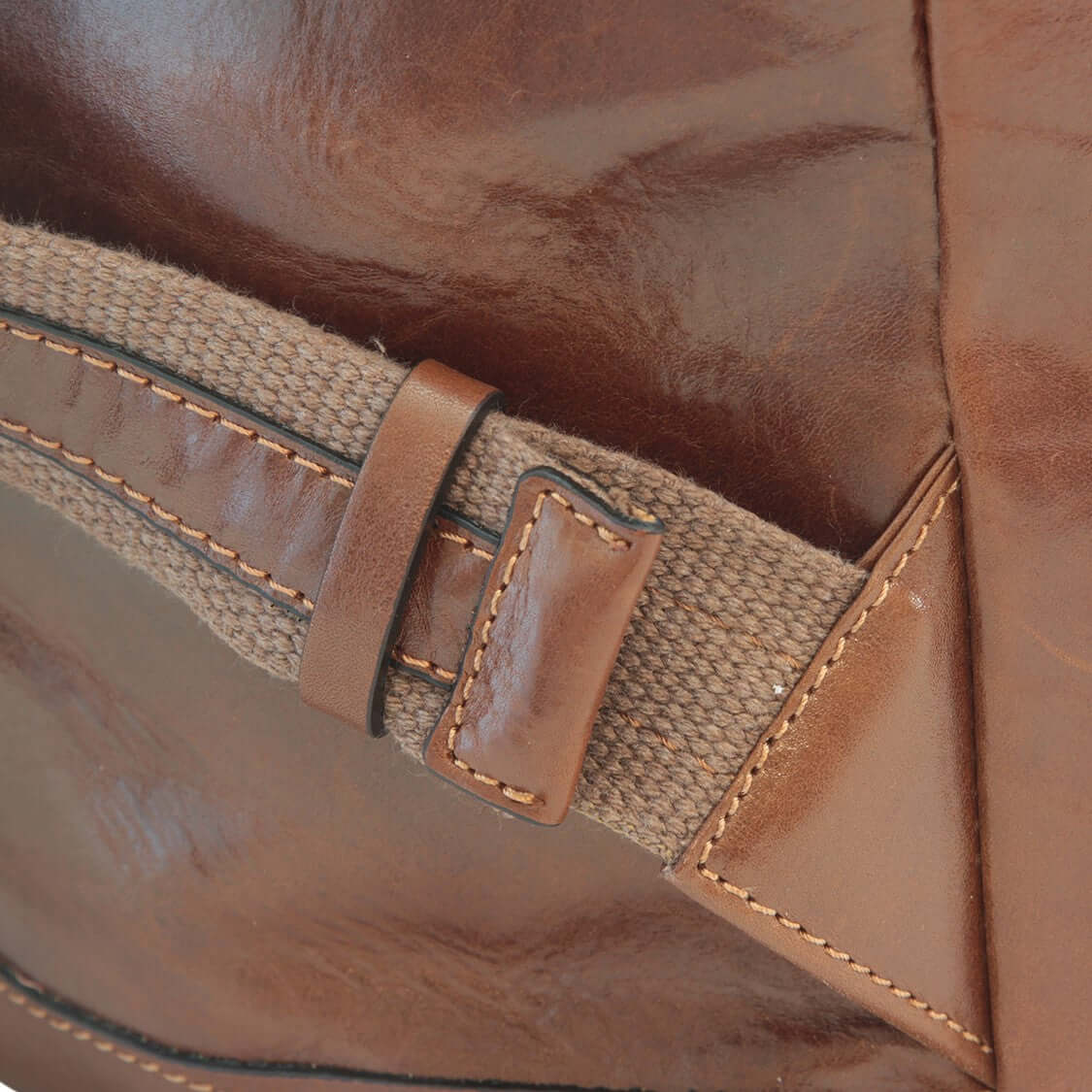 Dettaglio dello zaino in pelle marrone con tasche frontali, mostrante fibbia e cuciture in evidenza.