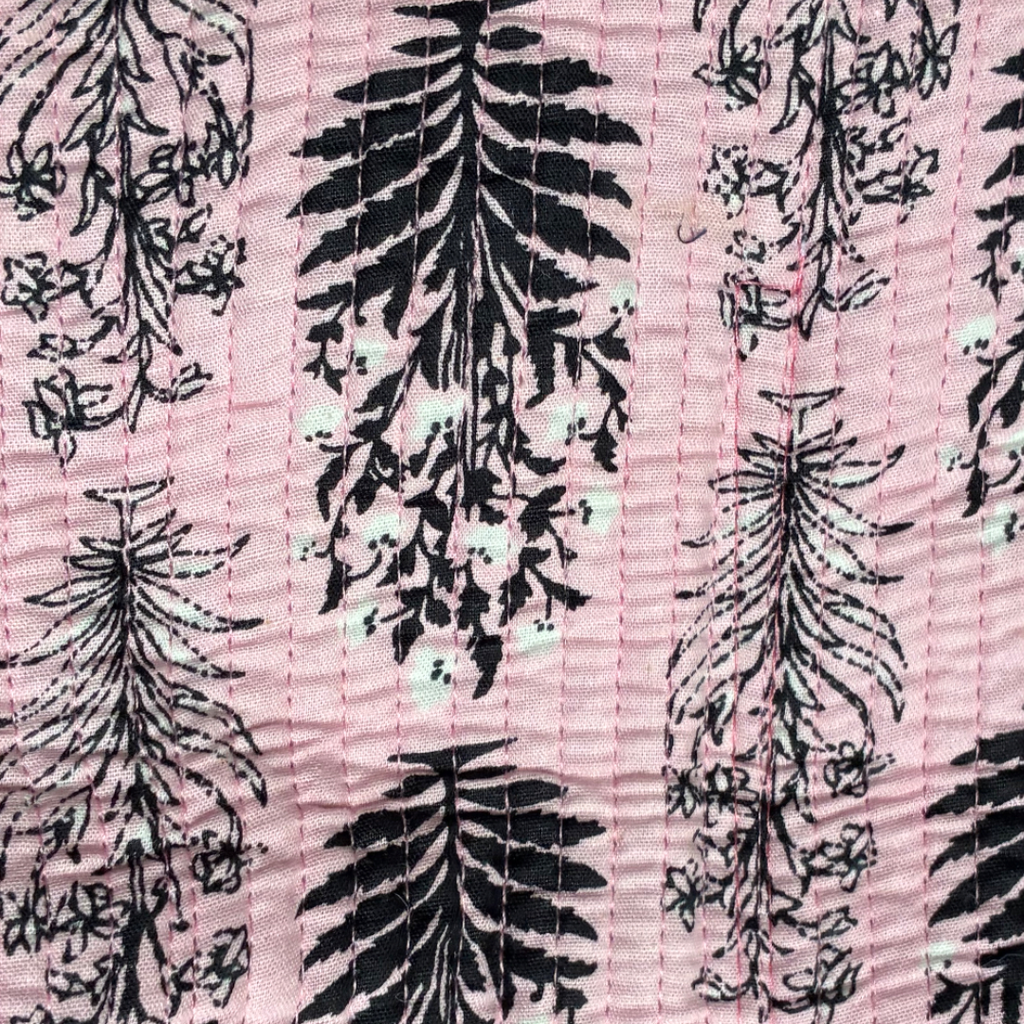 Patterned fabric featuring floral designs in black and white on a pink background, ideal for fashion and crafts.