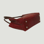 Borsa a spalla rossa bicolore con borchie metalliche sul fondo e angoli rinforzati