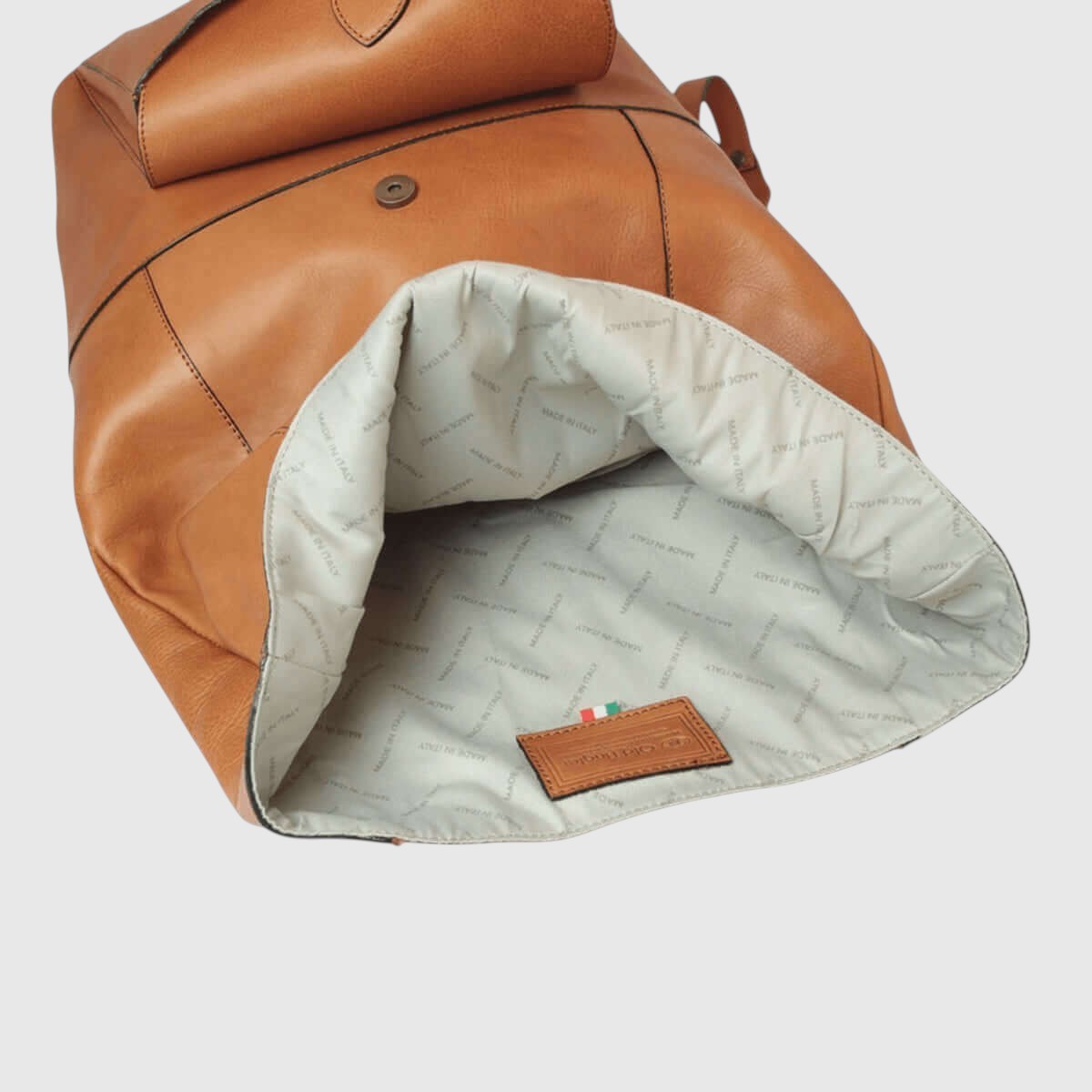 Interno dello zaino in pelle marrone con fodera chiara e passante etichetta in pelle