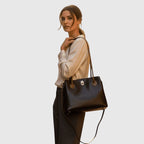 Borsa in pelle nera bicolore con due manici, chiusura metallica e tracolla.