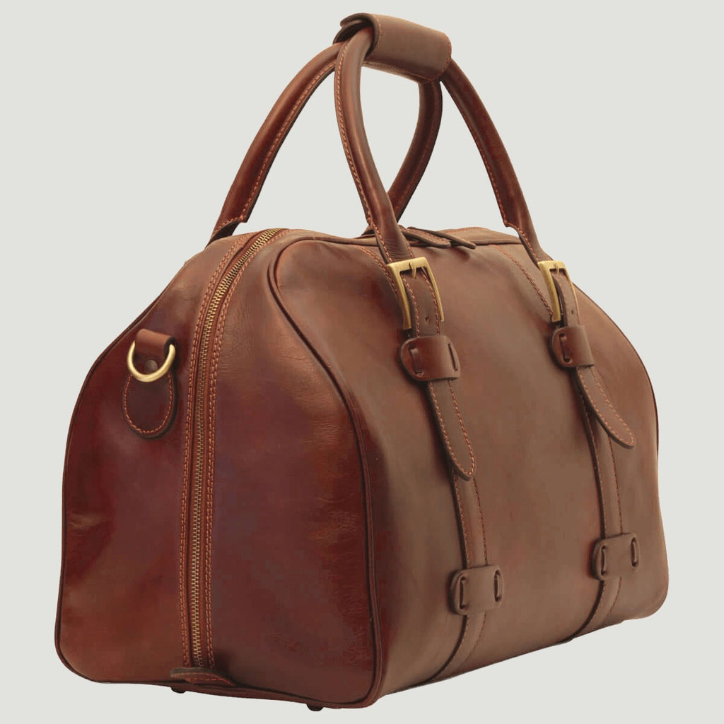 Borsone da viaggio in pelle marrone con doppie fibbie e tasche frontali.