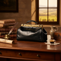Borsa in pelle nera con manico corto e hardware color ottone, su piano