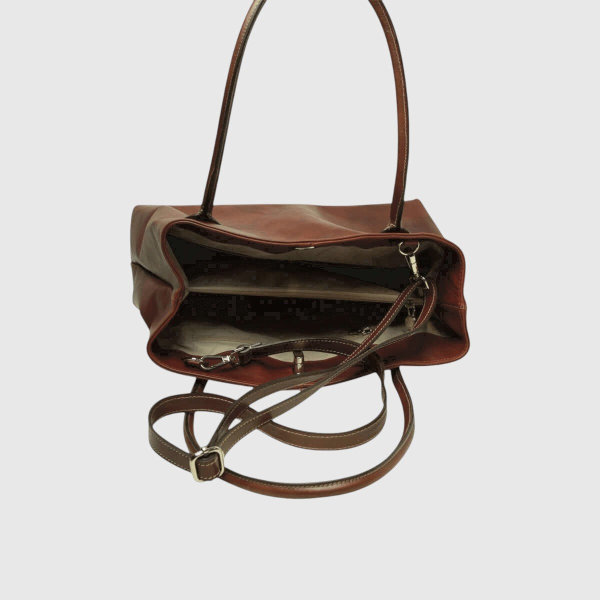 Borsa in pelle mogano aperta con interno scuro e tracolla regolabile