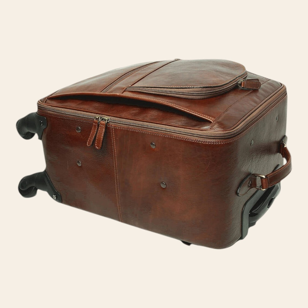Trolley in pelle marrone con profilo rigido, patta superiore e manico laterale; ruote.