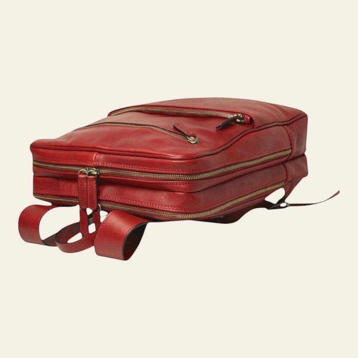 Mochila de piel de becerro en color rojo, colocada en horizontal con bolsillos frontales y dos compartimentos con cremallera