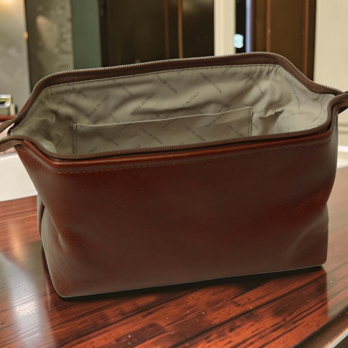 Astuccio beauty in pelle marrone, interno beige con fodera e zip aperta