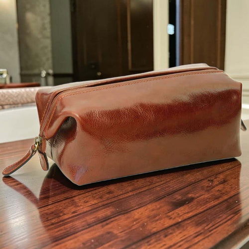 Astuccio beauty in pelle marrone con zip e tracolla, profilo arrotondato
