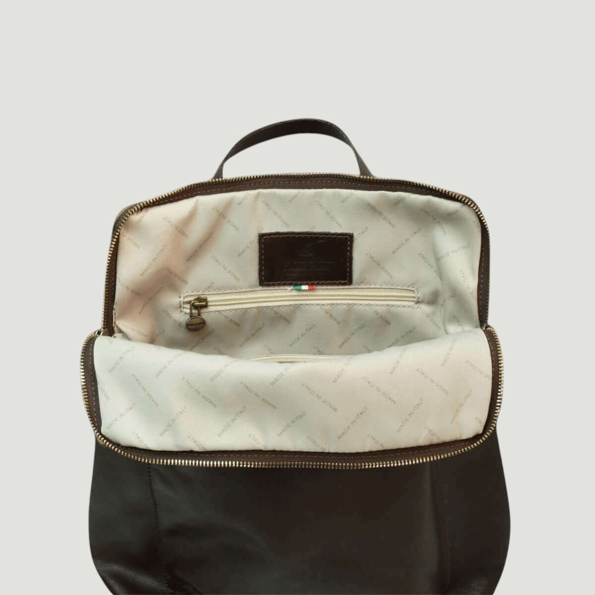 Interno dello zaino con fodera chiara, tasca e zip con bordo marrone