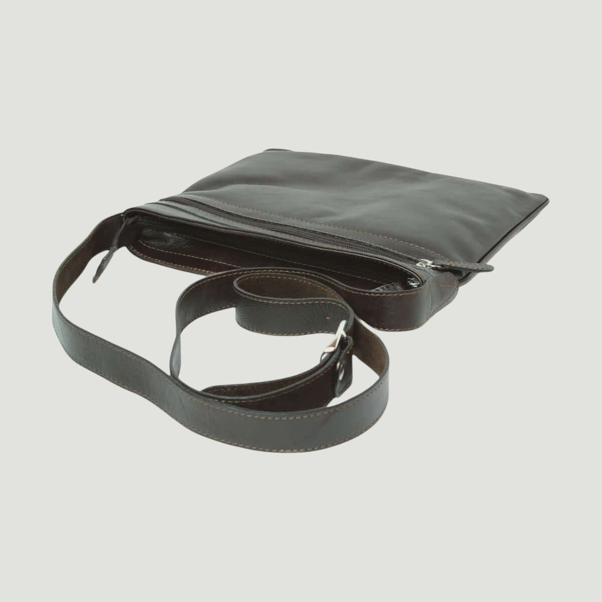 Borsa a tracolla in pelle scura vista dall’alto, tasca con zip e patta superiore