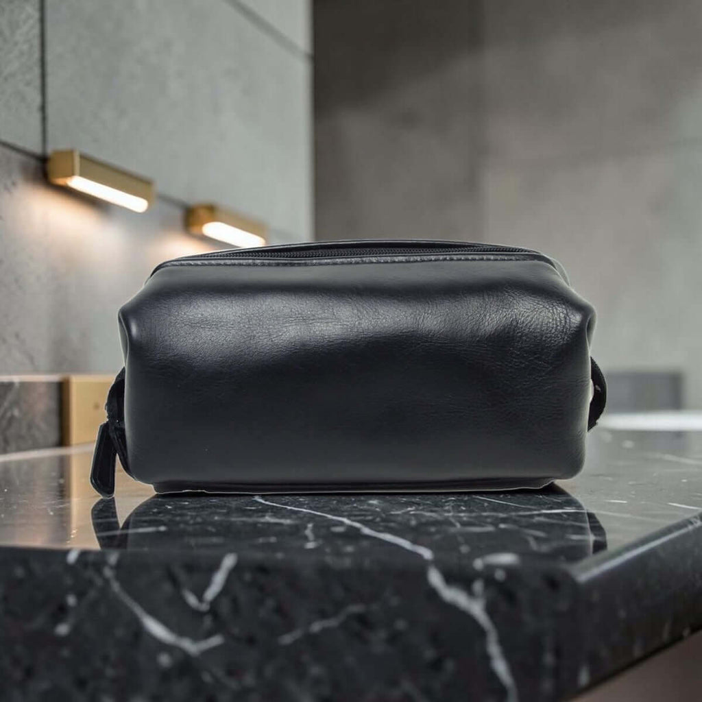 Porta cosmetici in pelle scura compatto con manici laterali e zip superiore.