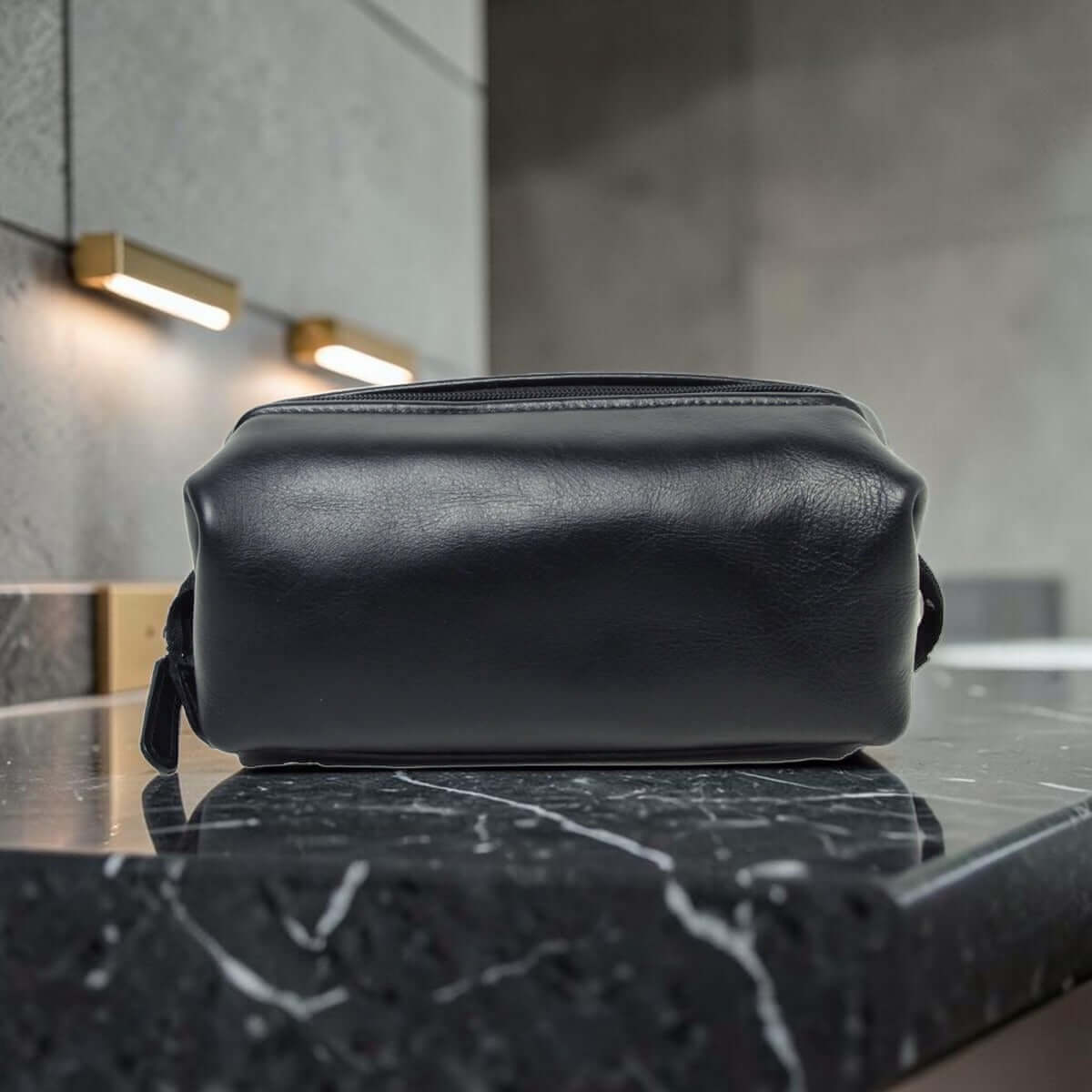Porta cosmetici in pelle scura compatto con manici laterali e zip superiore.