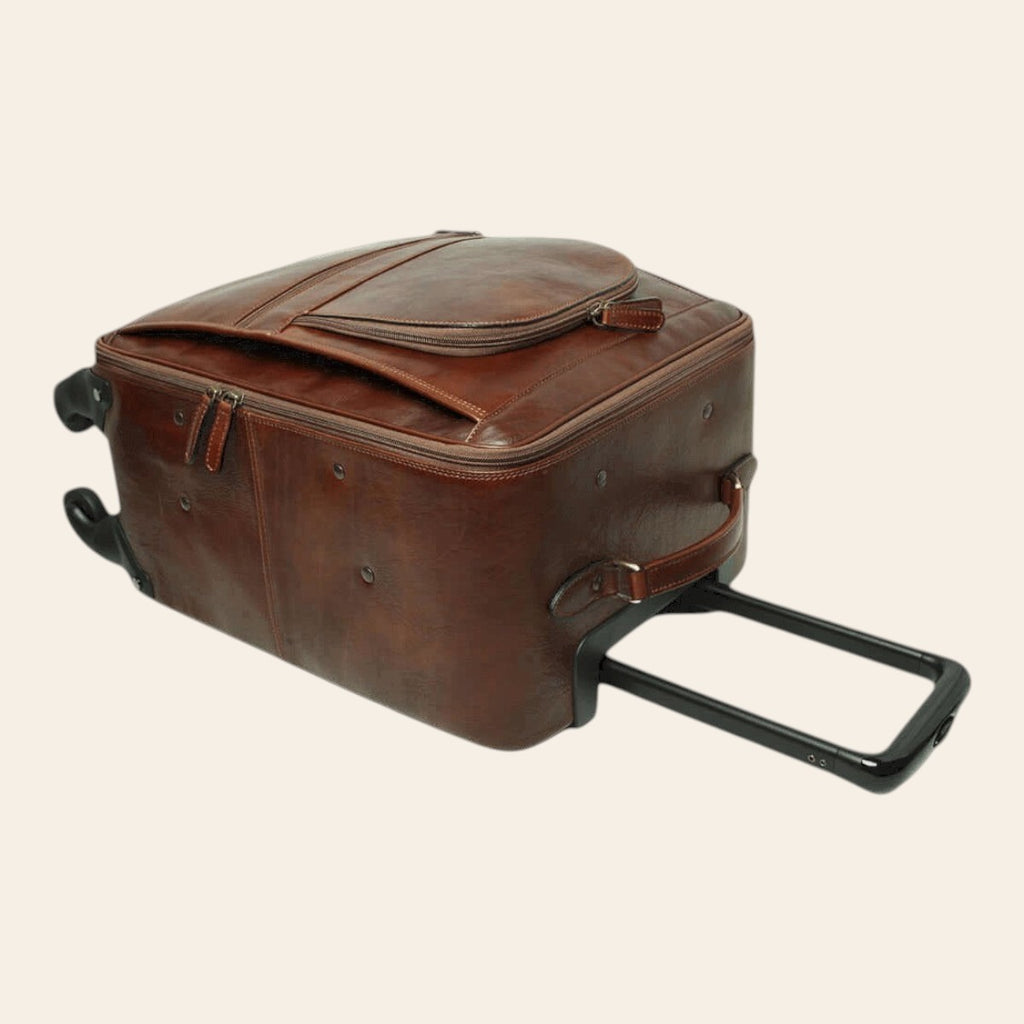 Trolley in pelle marrone con maniglia estesa e tracolla laterale; ruote.