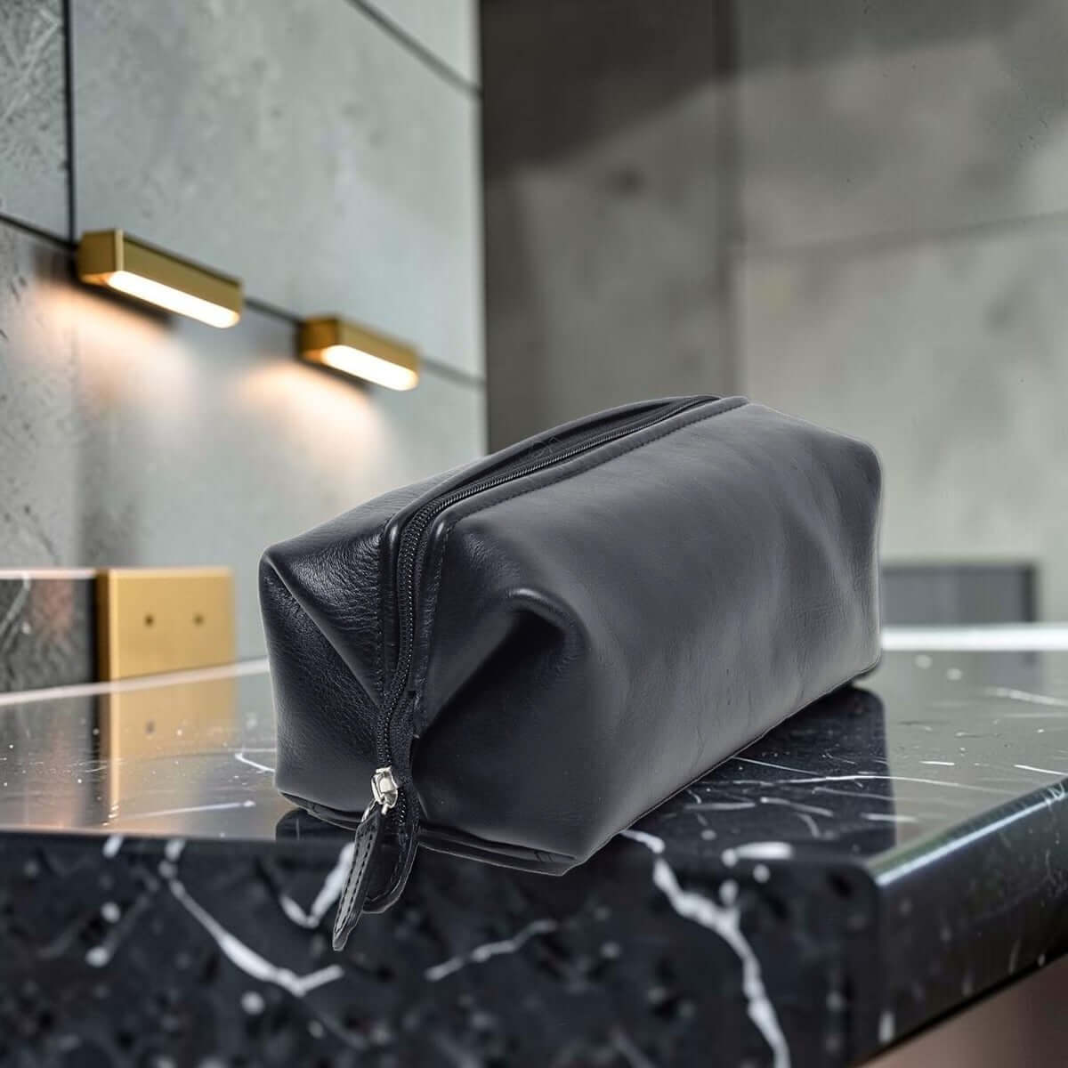 Porta cosmetici in pelle scura liscia con zip e tracolla.