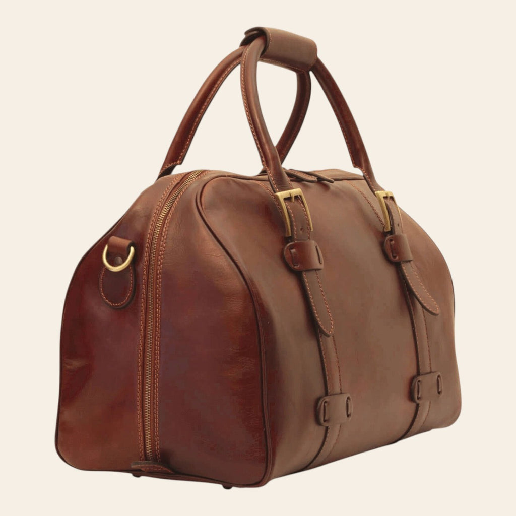 Borsone da viaggio in pelle marrone con doppie fibbie e tasche frontali.